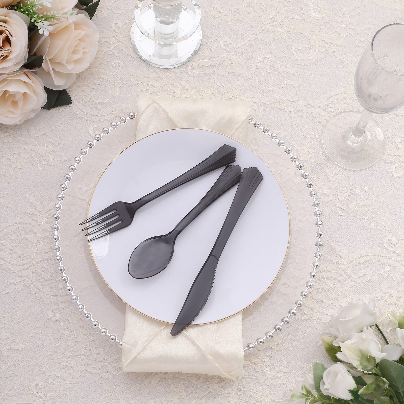 Transparent black disposable cutlery set on a white plate with elegant decor.