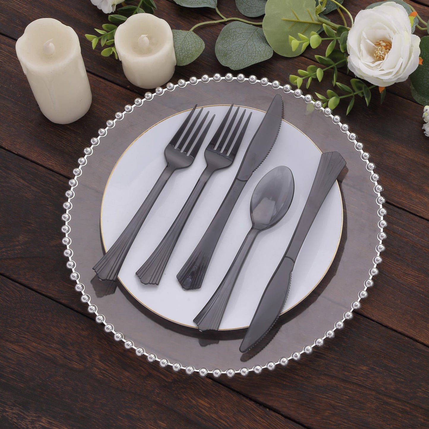 Transparent black disposable plastic cutlery set on a decorative plate.