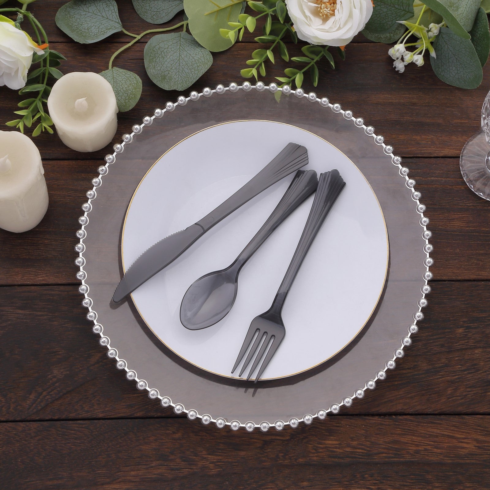 Transparent black disposable cutlery set on a plate with floral decor.