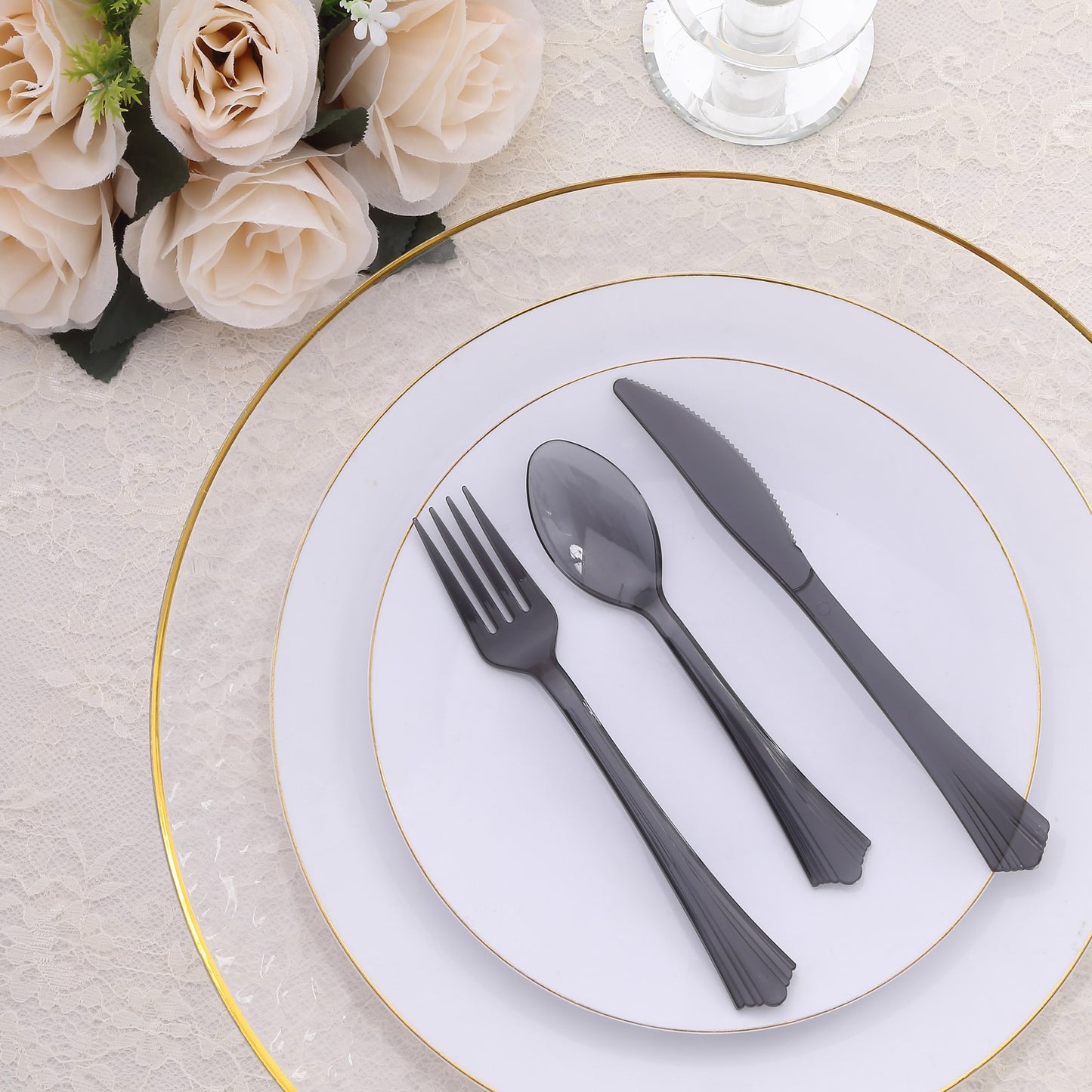 Transparent black disposable plastic cutlery set on a white plate.