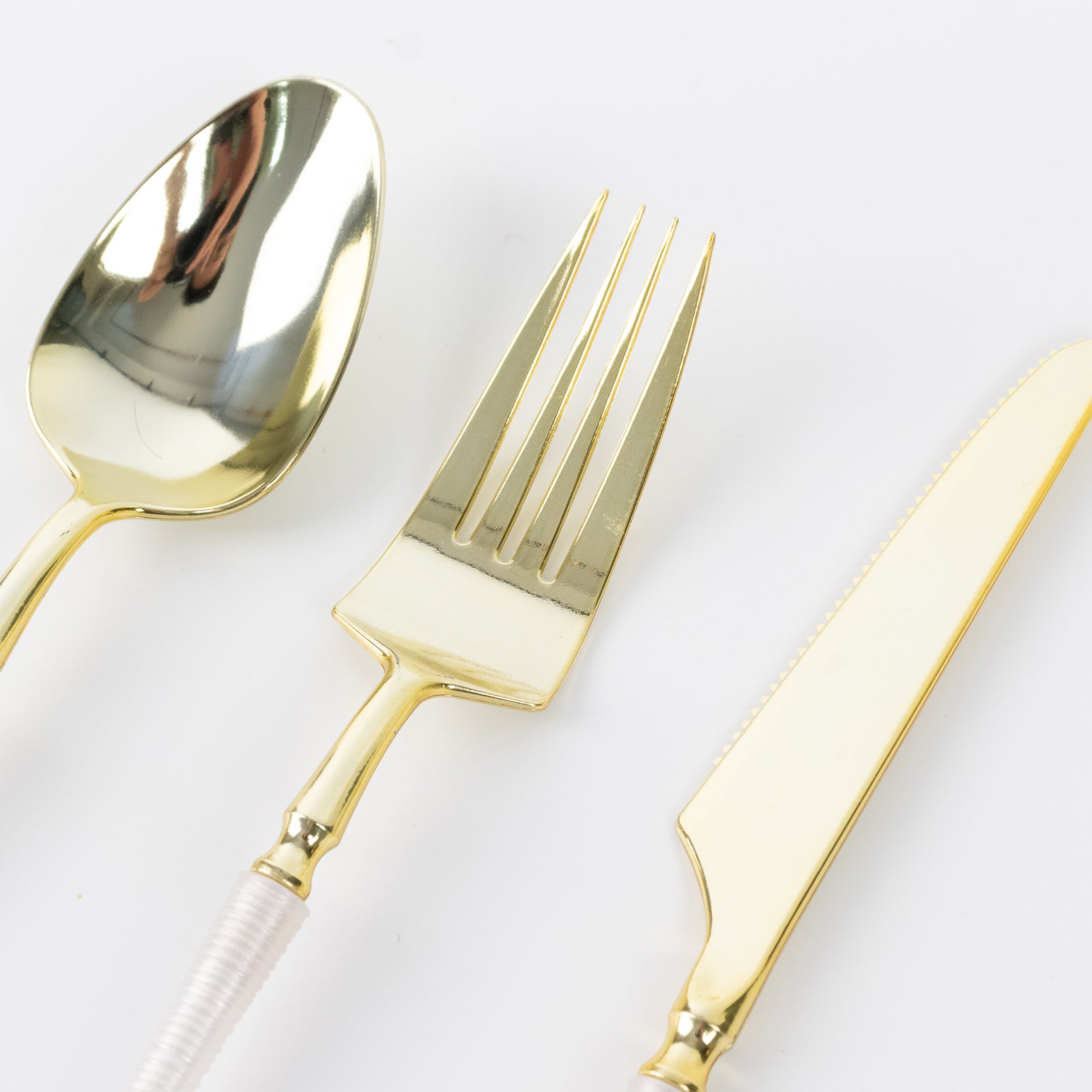 Gold plastic cutlery set with white handles, including fork, spoon, and knife.