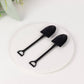 Black mini shovel plastic ice cream spoons on a white plate.