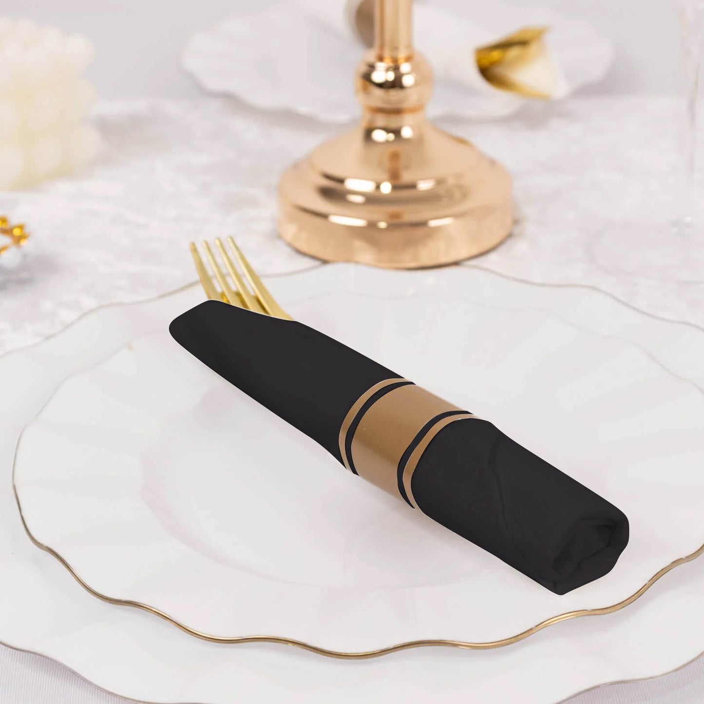 Gold and black disposable cutlery set with napkins on a decorated table.