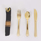Gold disposable cutlery set with black napkin.