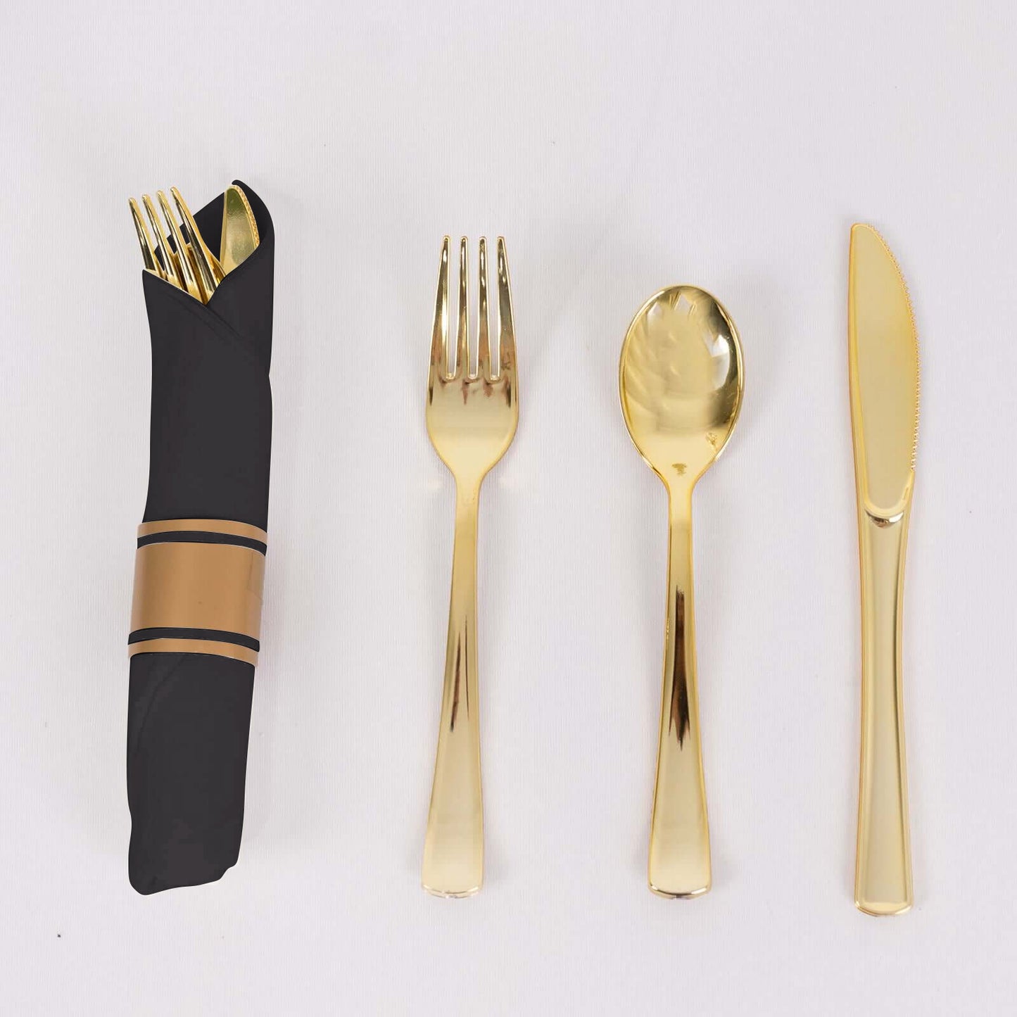 Gold disposable cutlery set with black napkin.