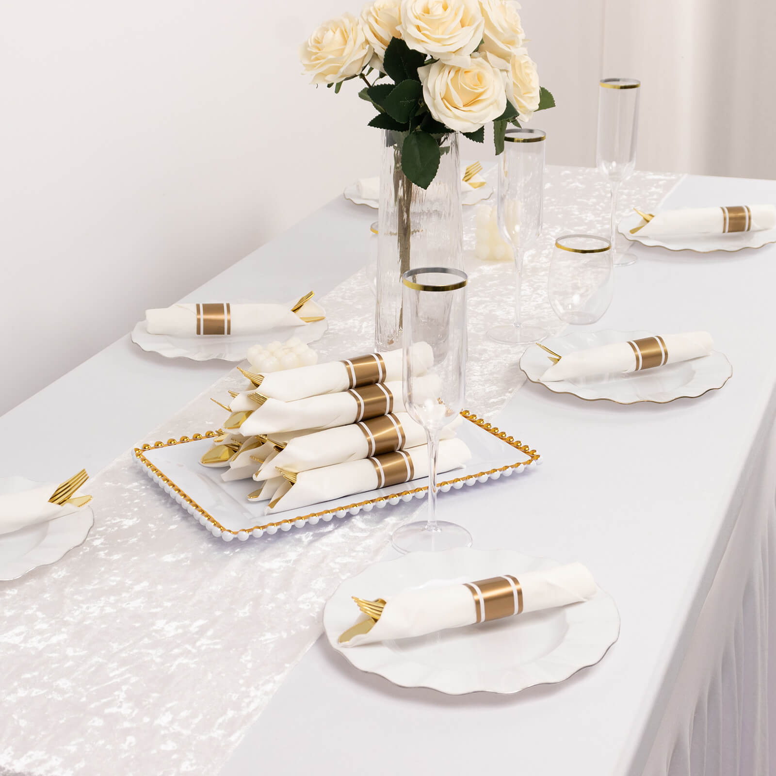 Gold disposable cutlery set with white napkins on a festive table setting.