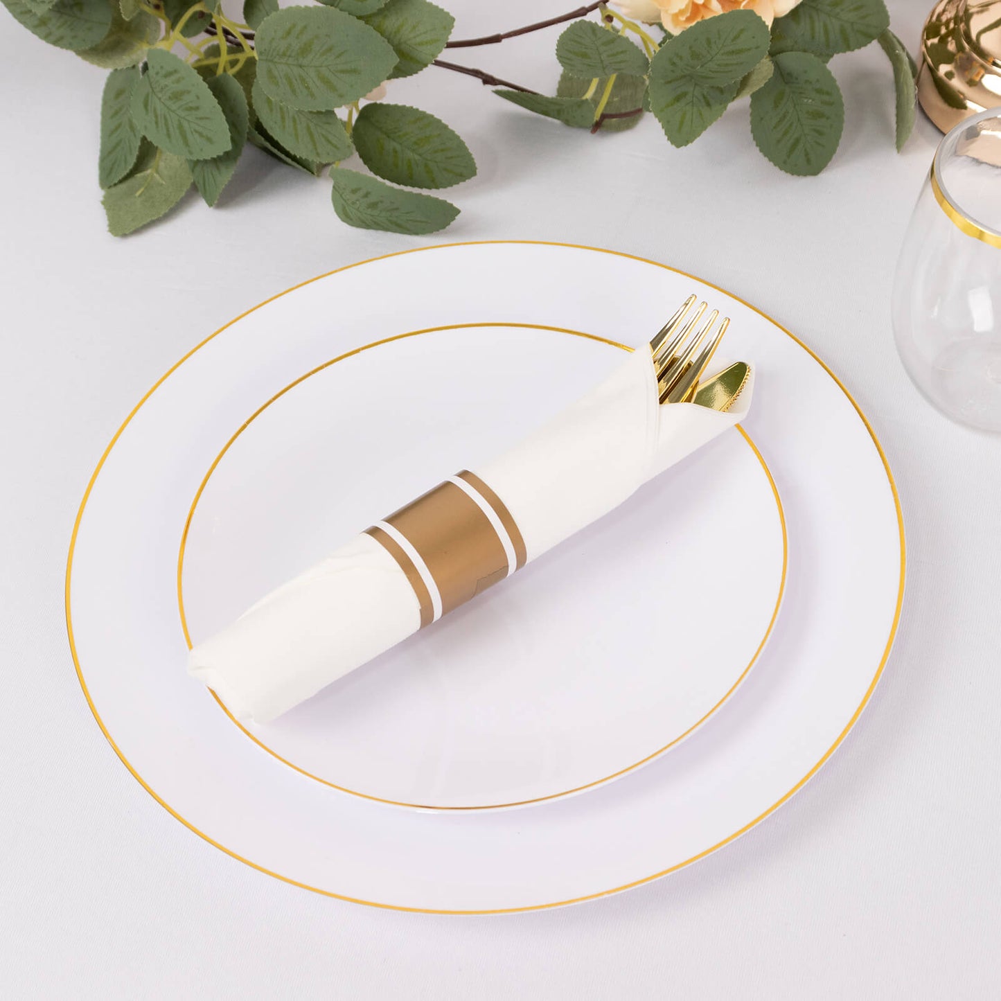 Gold disposable cutlery set with white napkins on a table setting.
