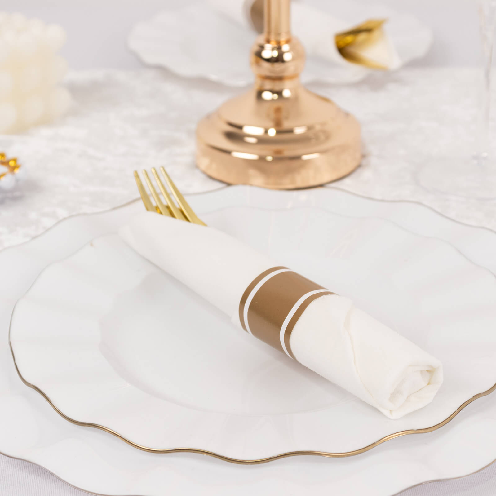 Gold disposable cutlery set with white napkins on an elegant table setting.