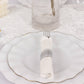 Set of silver disposable cutlery with white napkins on a decorative plate.