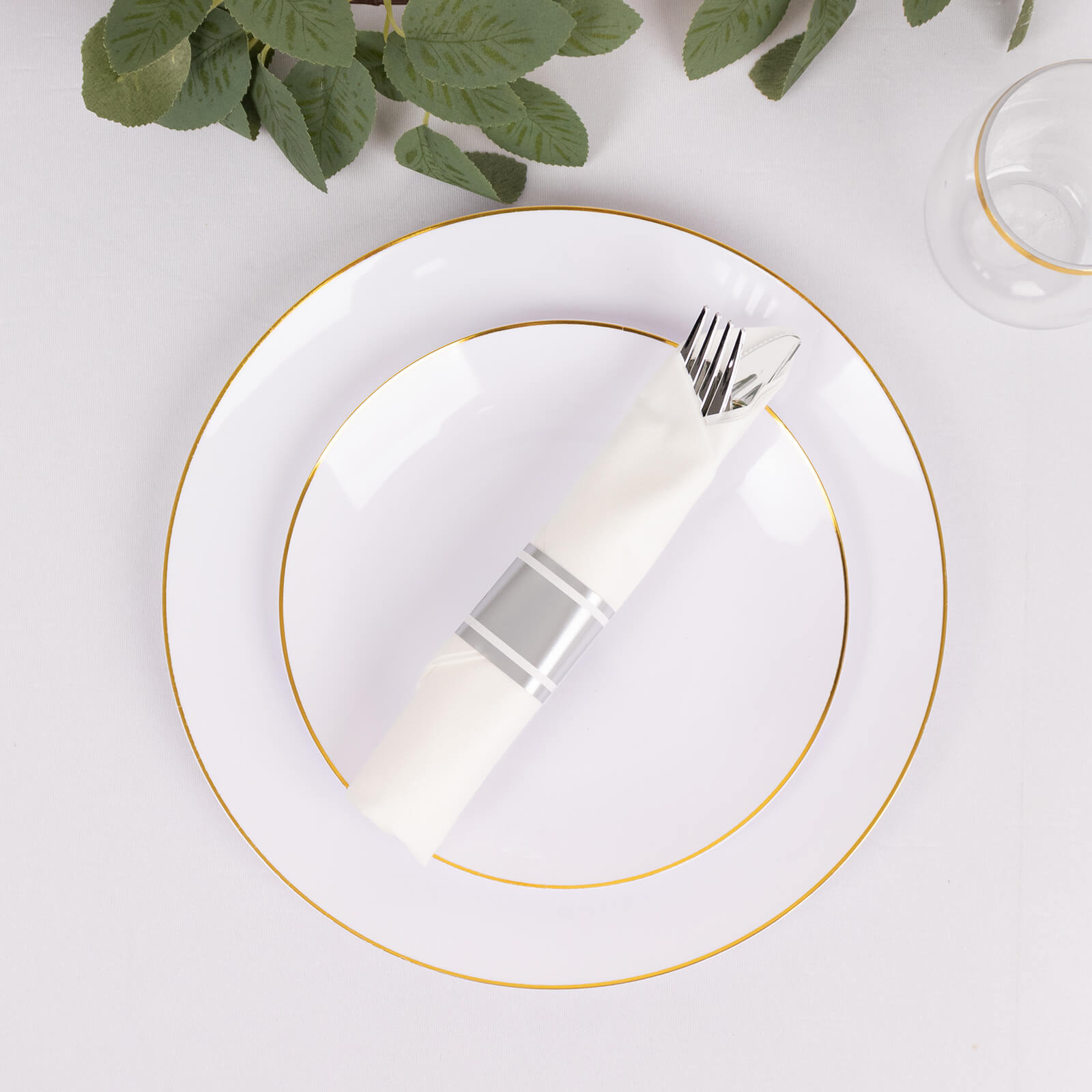 Set of 24 silver plastic cutlery with white napkins on a plate.