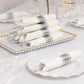 Silver disposable cutlery set with white napkins on a decorative tray.