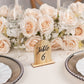Natural wood table number 6 surrounded by blush roses at an elegant event setting.