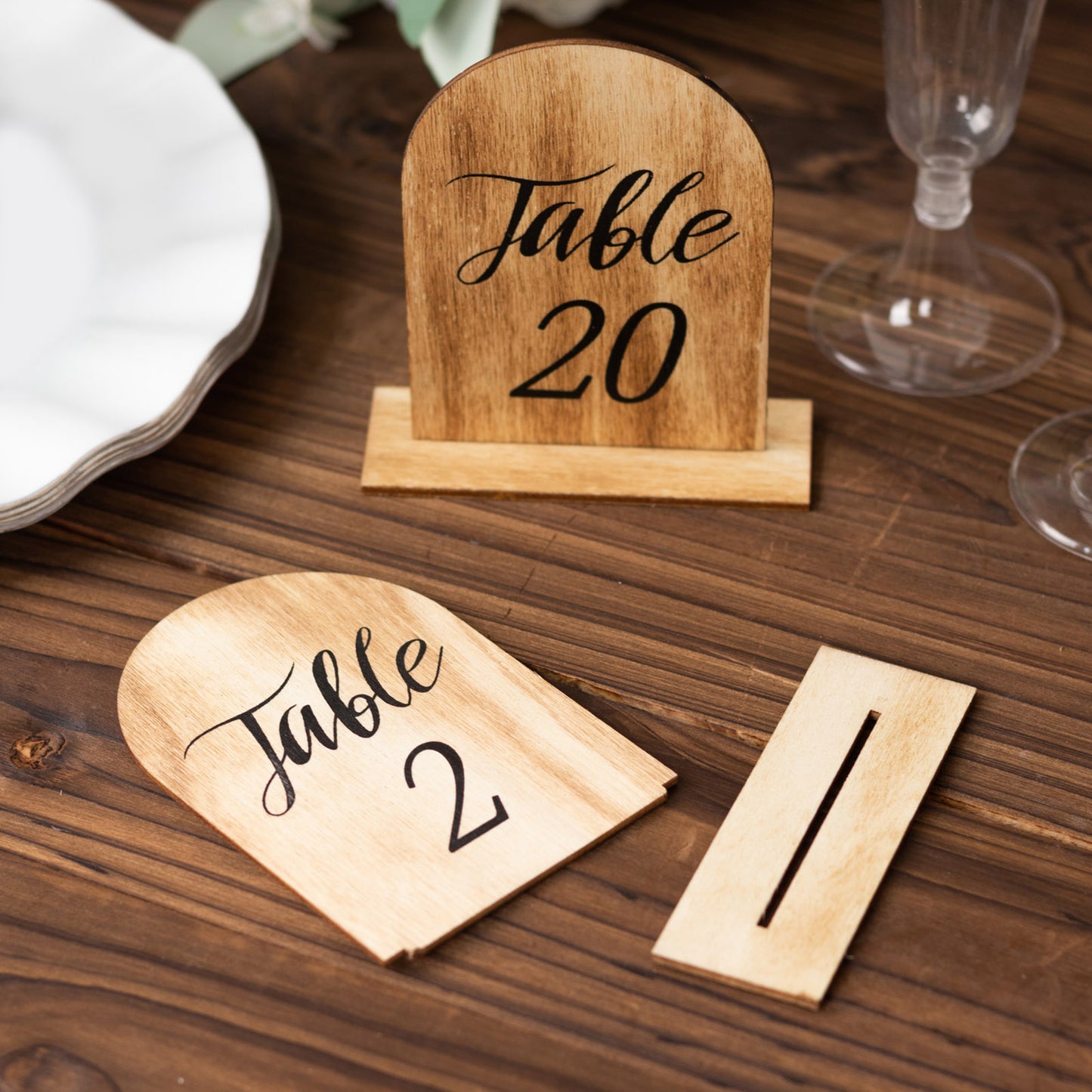 Natural rustic wooden table numbers for weddings, 1-20, on a wooden table.