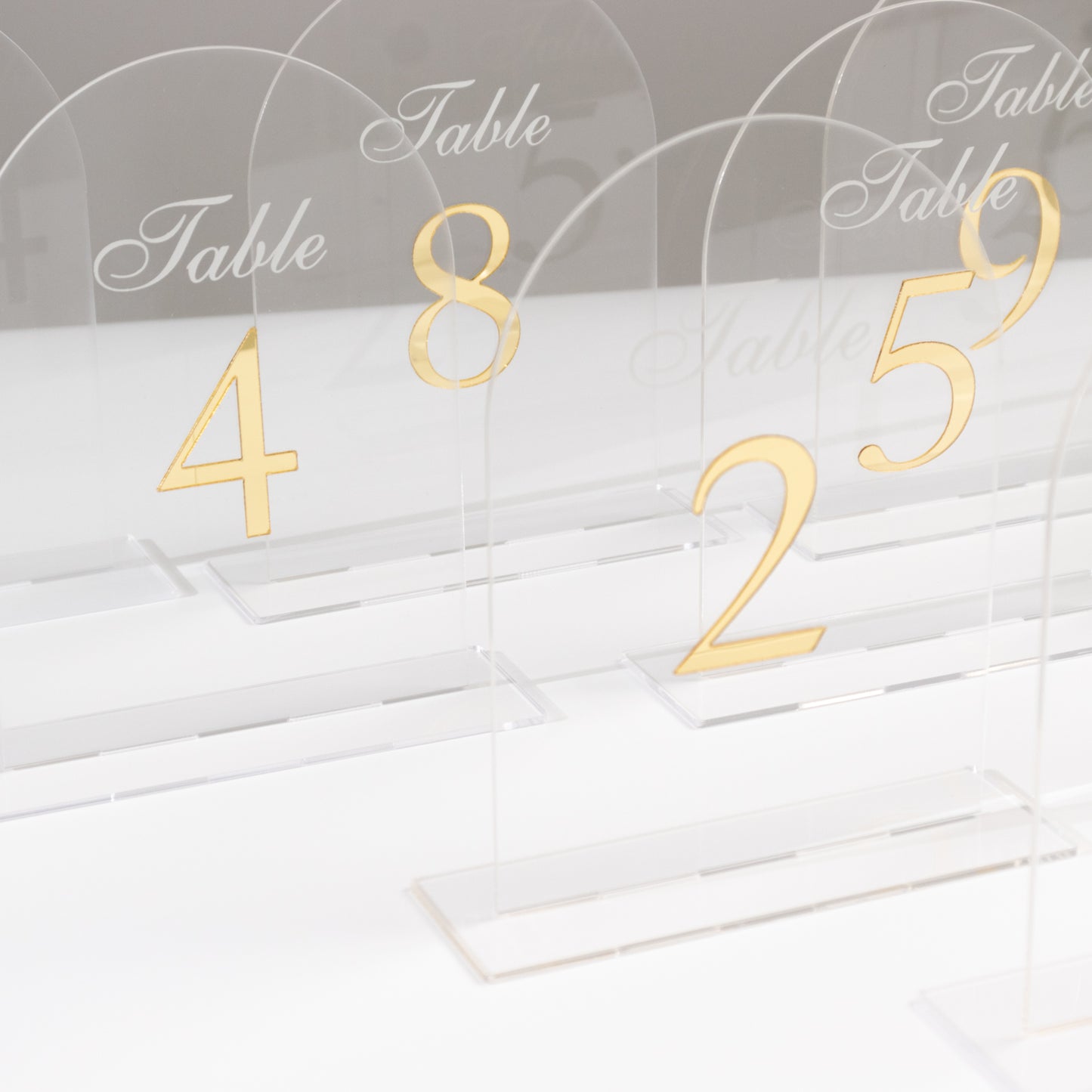 Clear arch acrylic table numbers with gold print, perfect for wedding receptions.