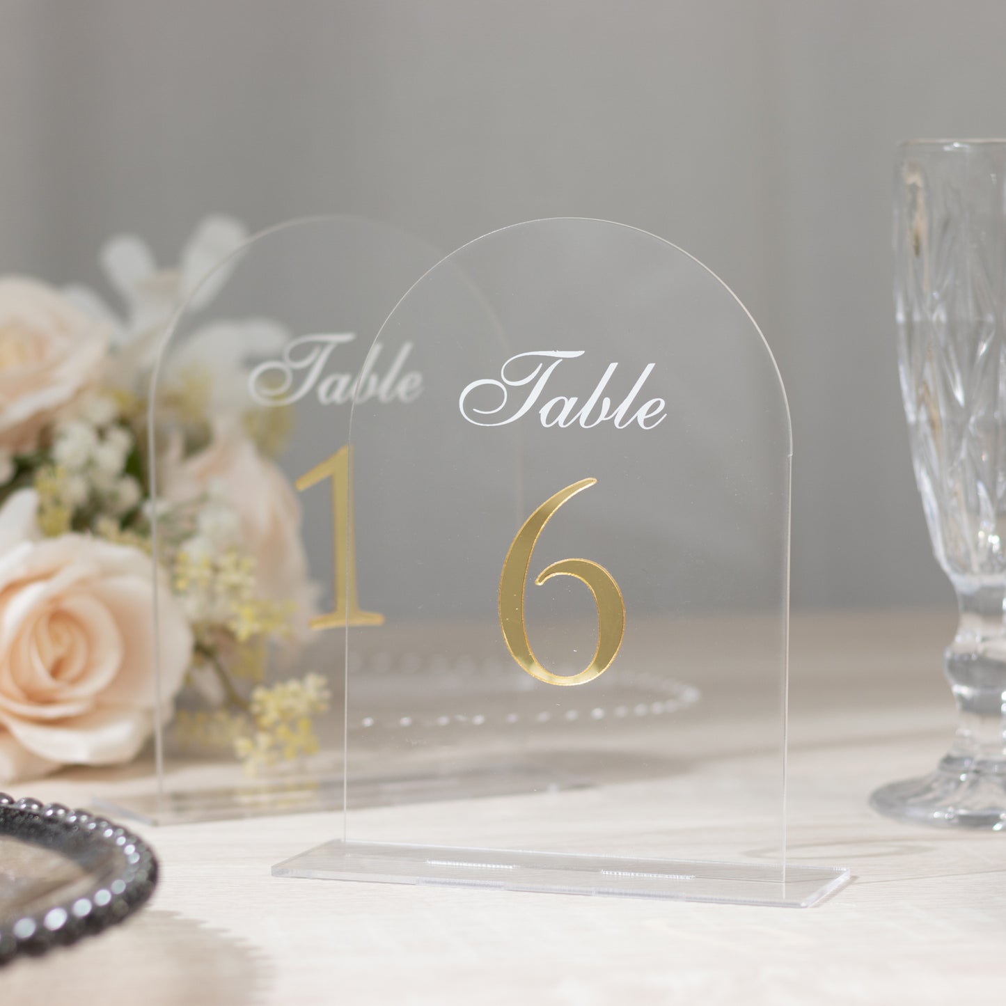 Clear arch acrylic table number with gold print, elegant wedding reception sign.