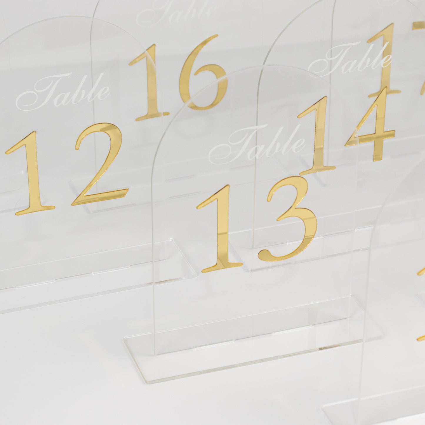Clear arch acrylic table numbers with gold print, numbers 11-20.