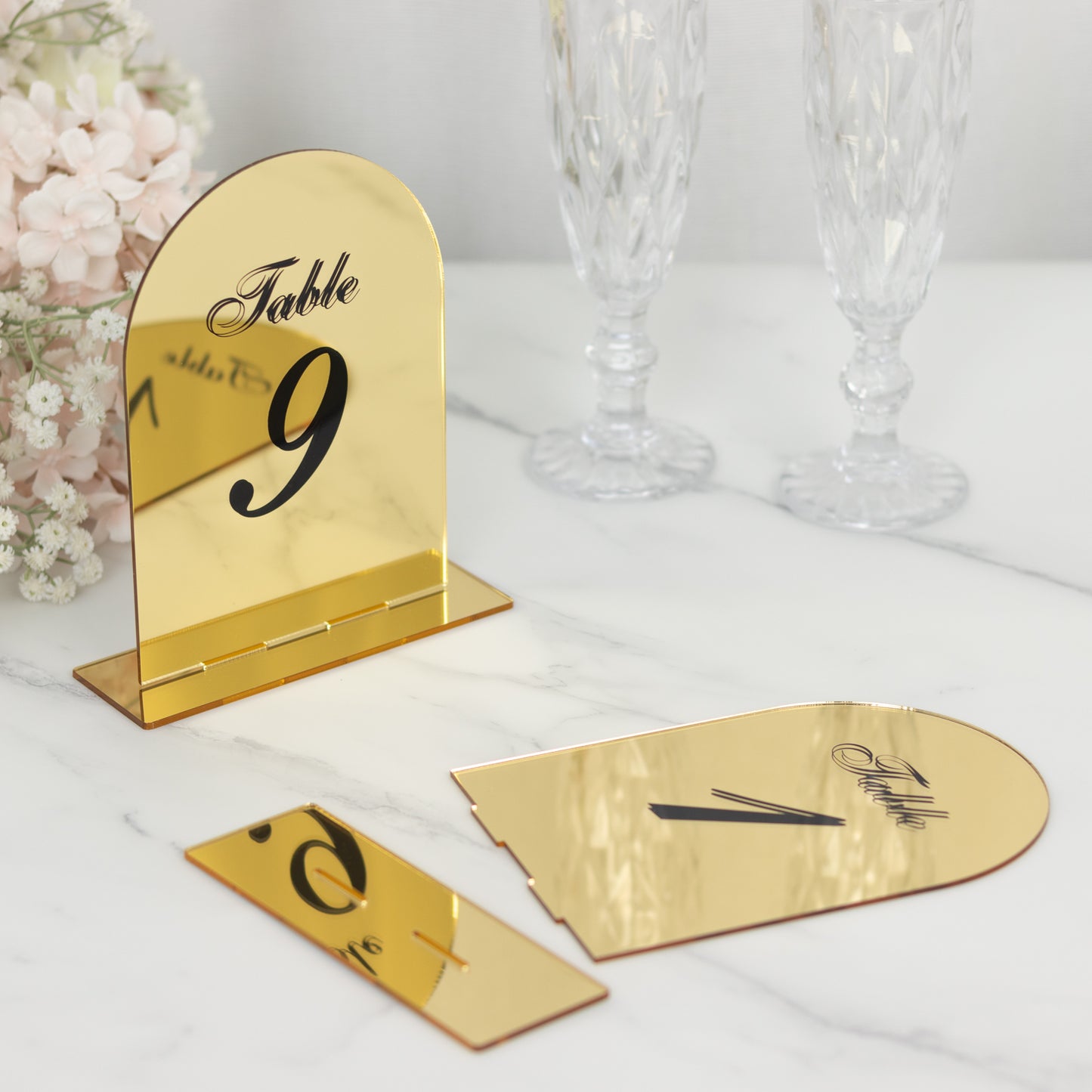 Gold mirror table number 9 with black print on a marble surface.