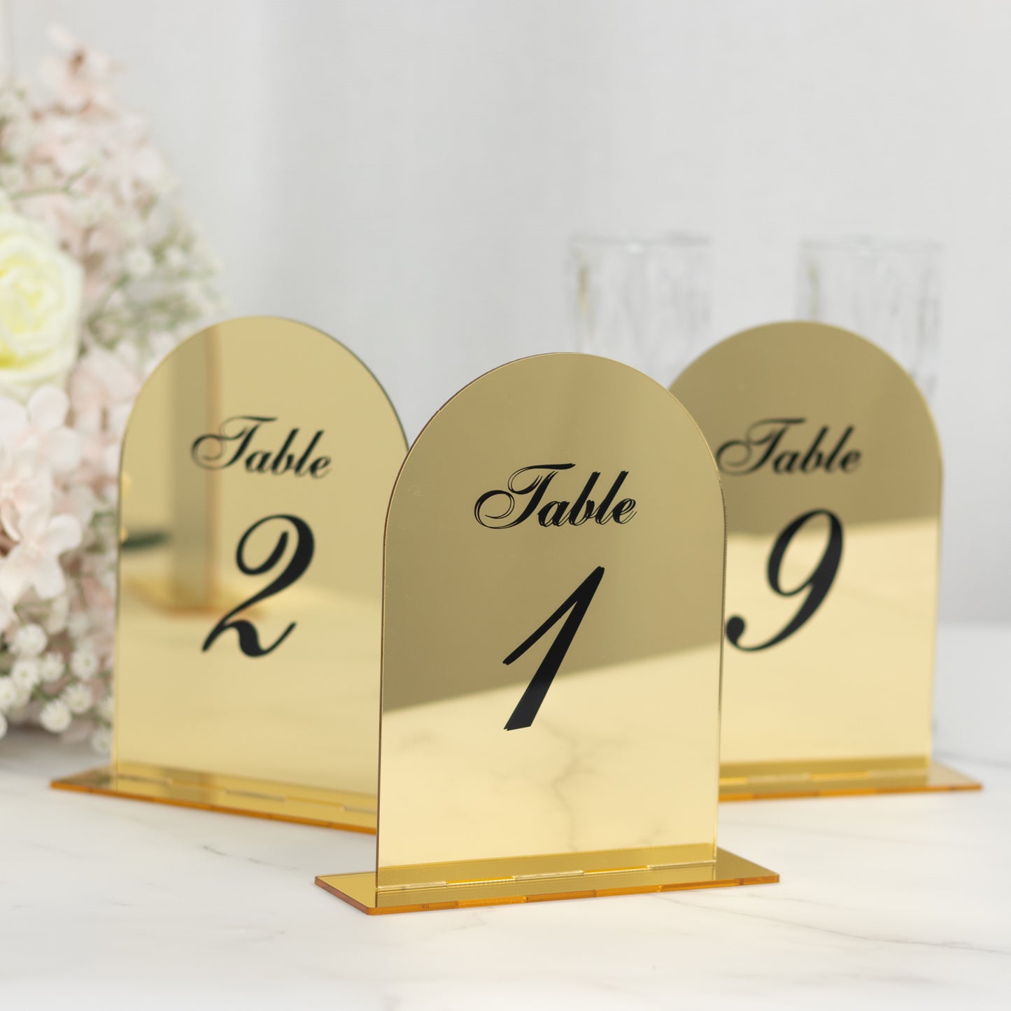 Gold mirror arch table numbers with black print for weddings.