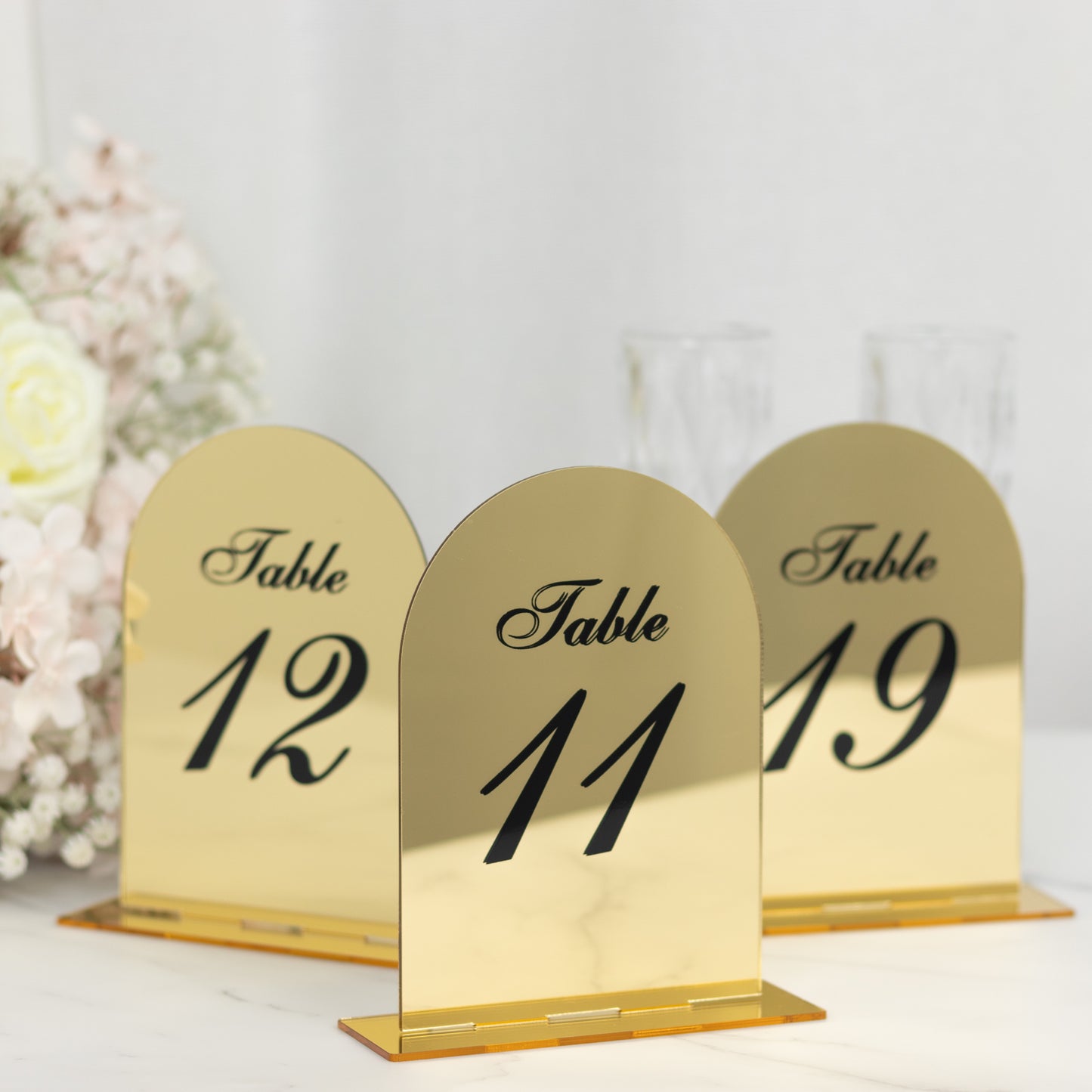Gold mirror arch table numbers with black print for wedding reception.