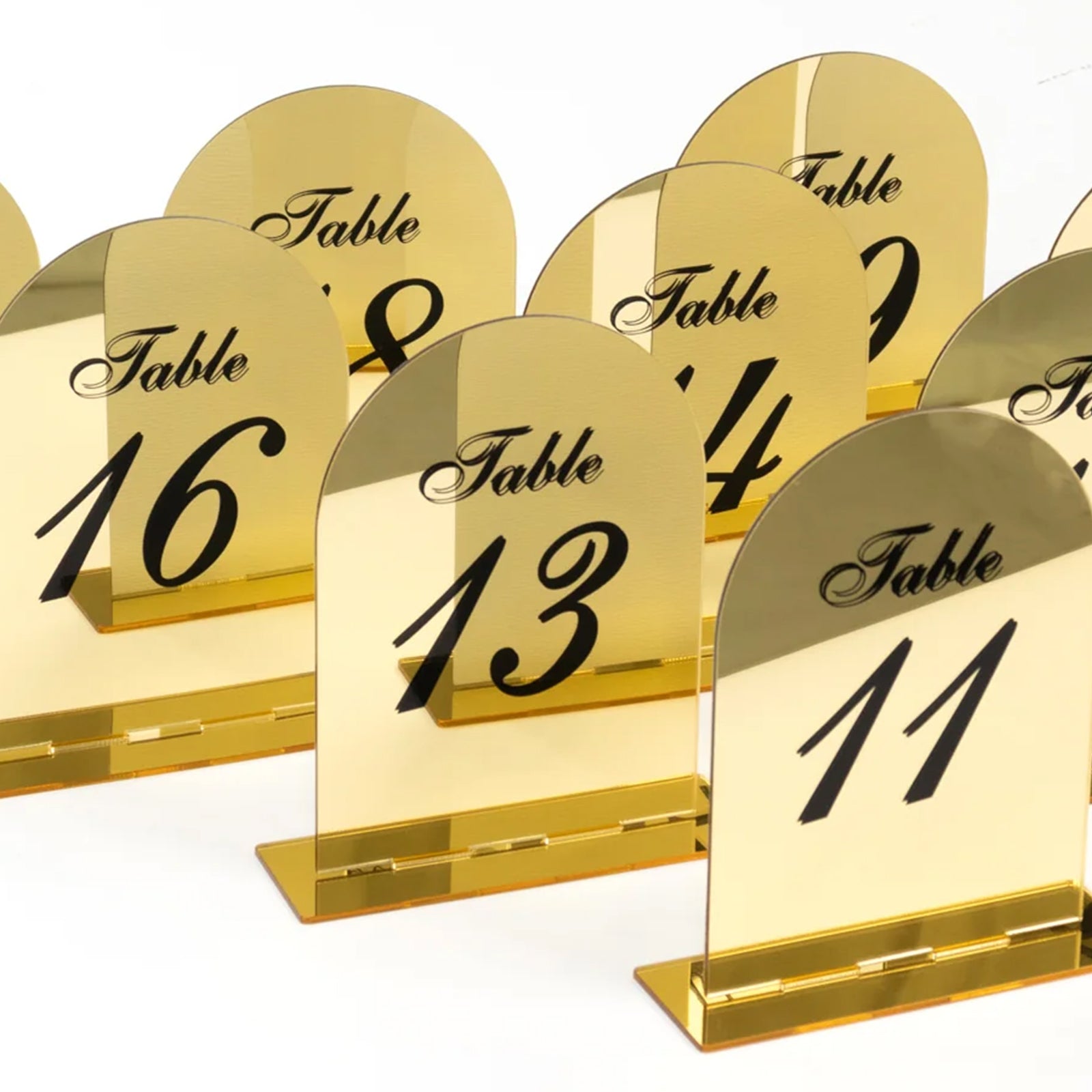 Gold mirror arch table numbers with black print for wedding reception.