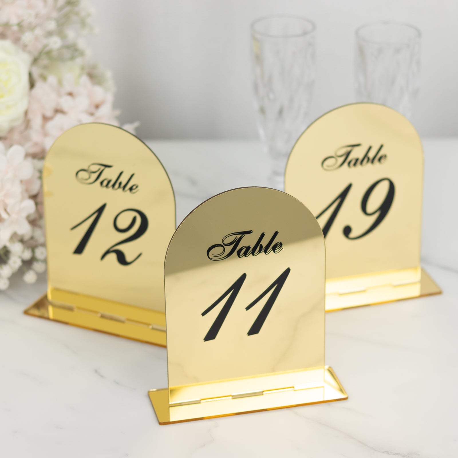 Gold mirror arch table numbers with black print for wedding reception.