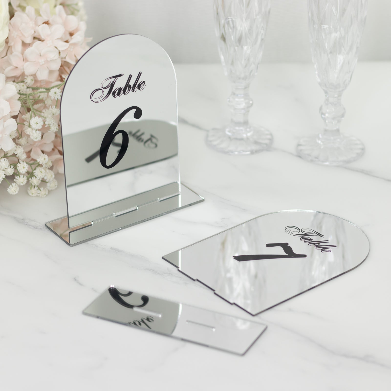 Silver mirror arch table numbers with black print for weddings.