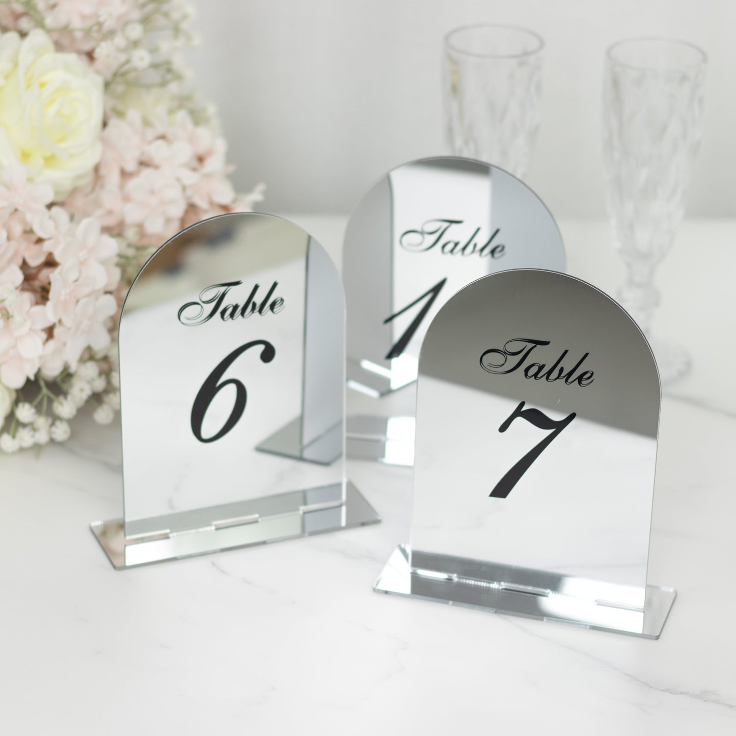 Silver mirror table numbers with black print for weddings.