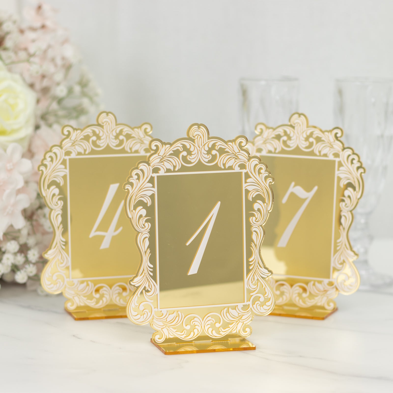 Gold mirror table numbers with white print and lace border, wedding décor.
