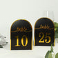 Black table numbers with metallic gold foil, displaying numbers 10 and 25.