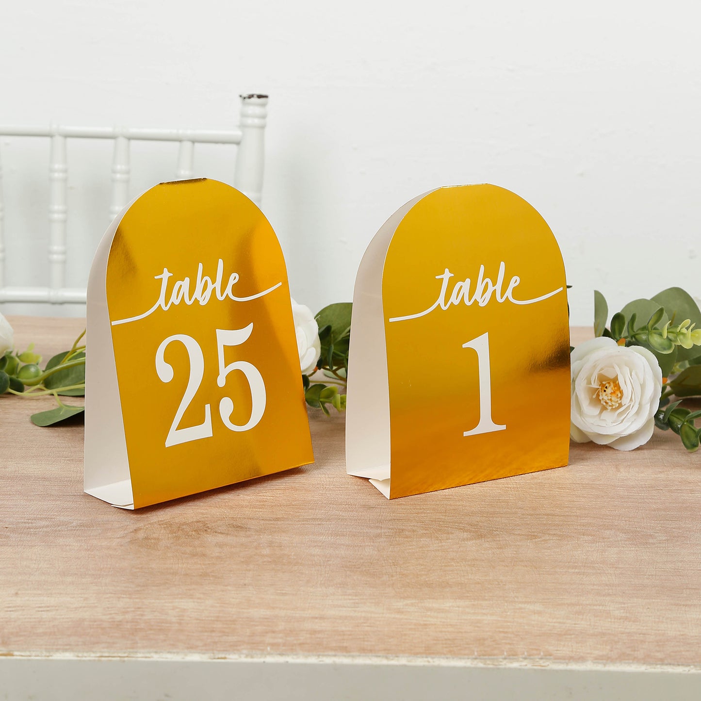 Metallic gold table number cards 1-25 on a wooden table.