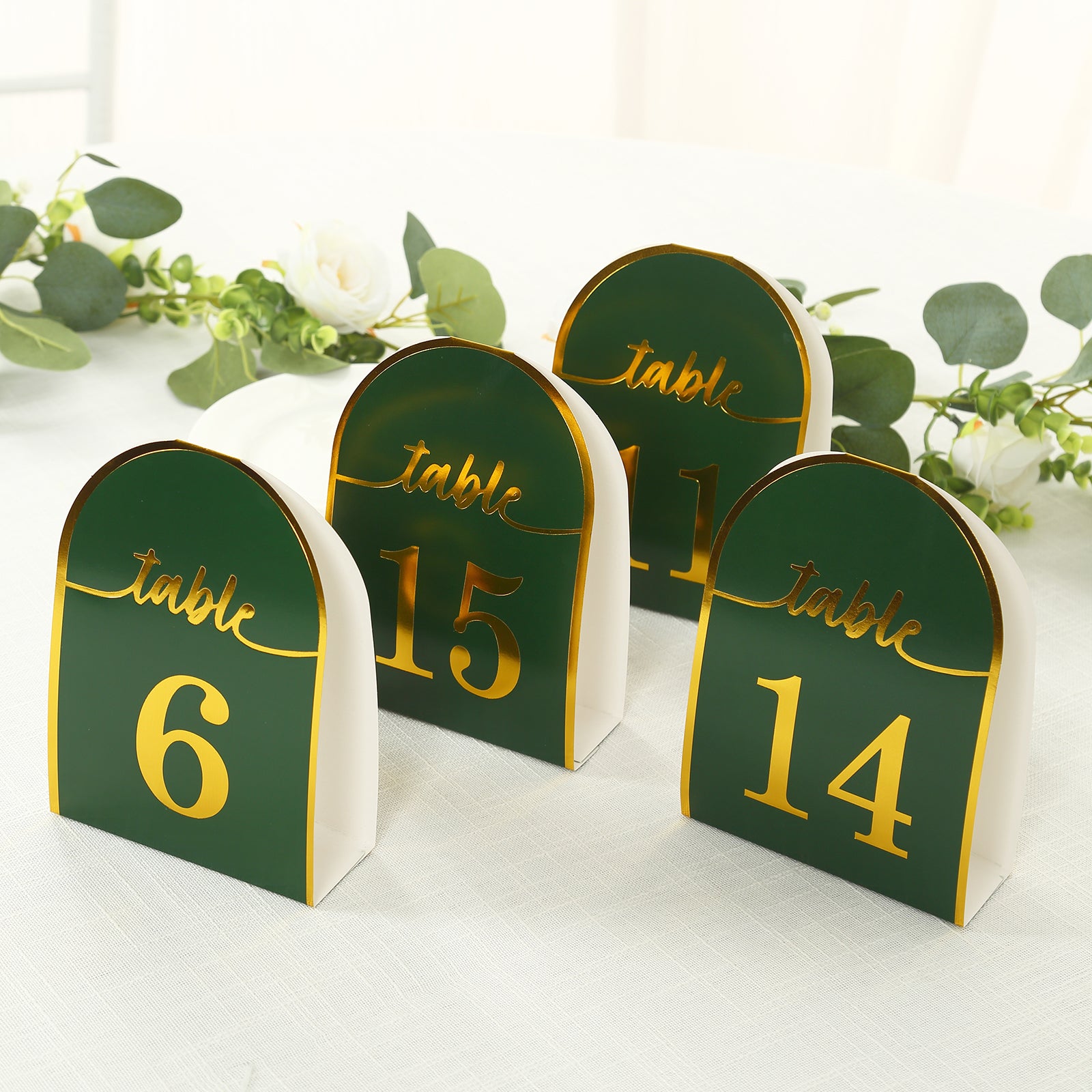Hunter emerald green table numbers with gold foil, standing on a table.