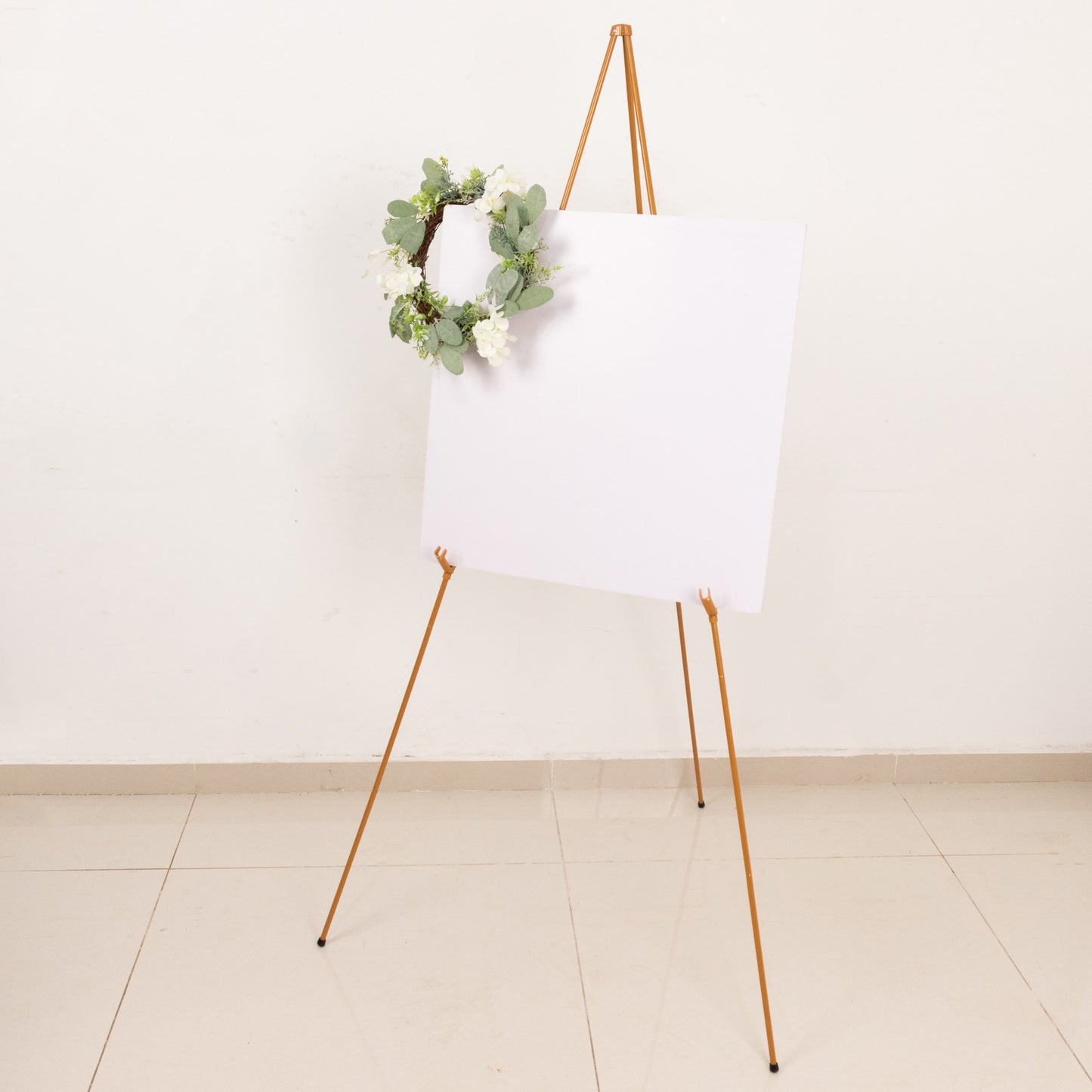 Gold metal easel stand with collapsible tripod design.