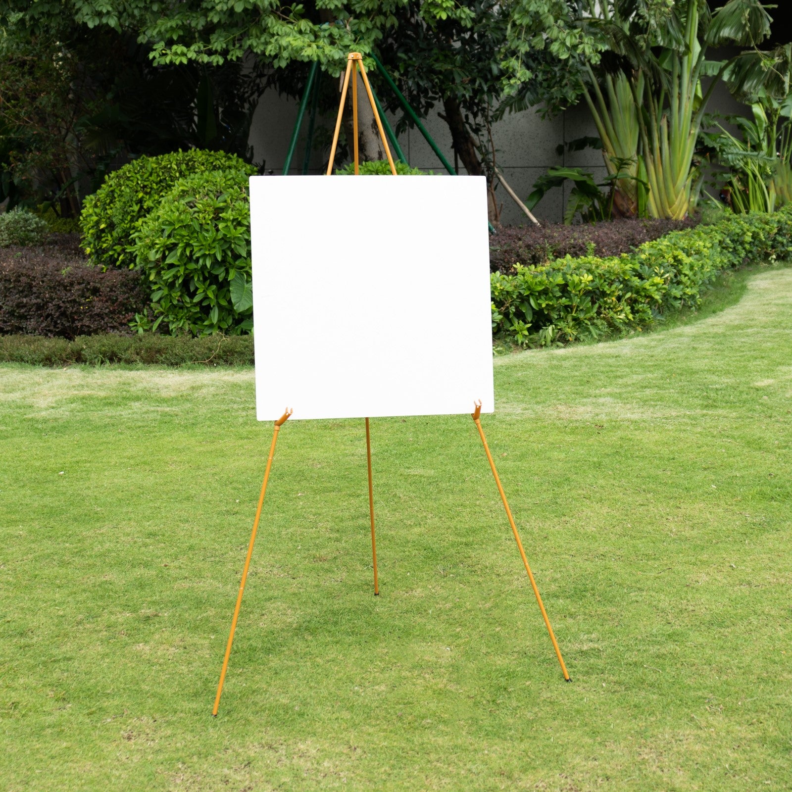 Gold metal easel stand in a garden setting.