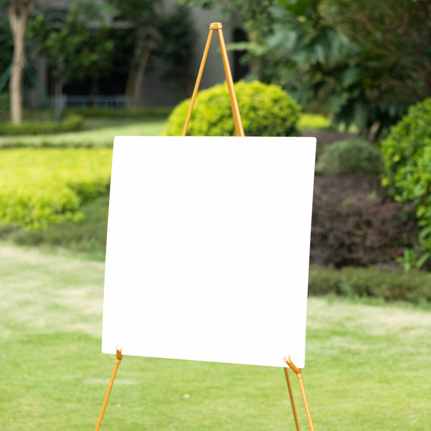 Gold metal sign holder easel stand in a garden setting.