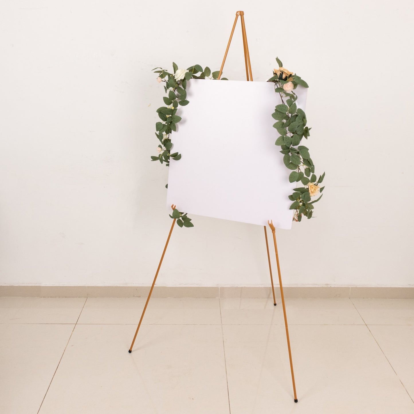 Gold metal easel stand with greenery decoration.