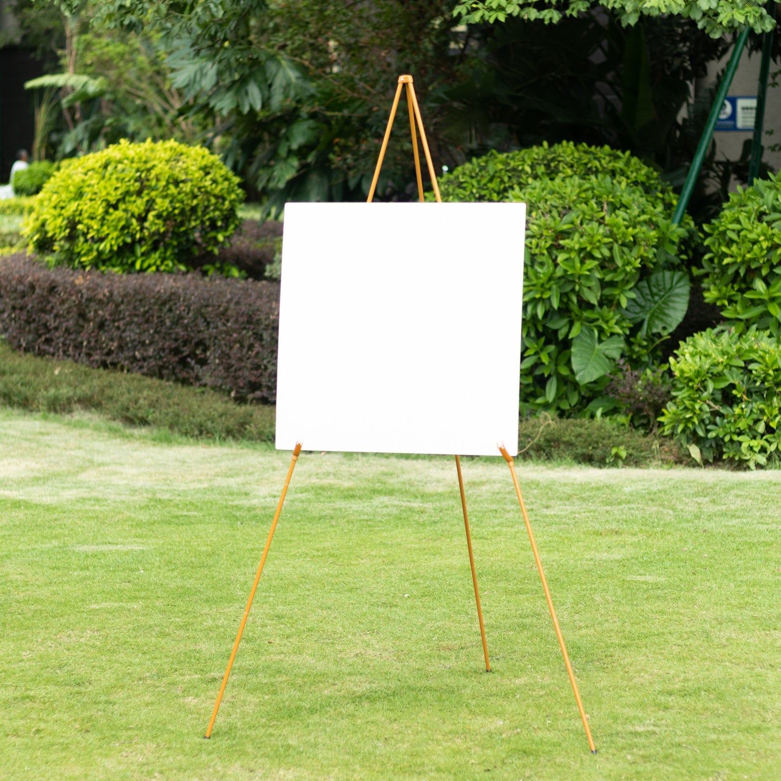 Gold metal easel stand in a garden setting.