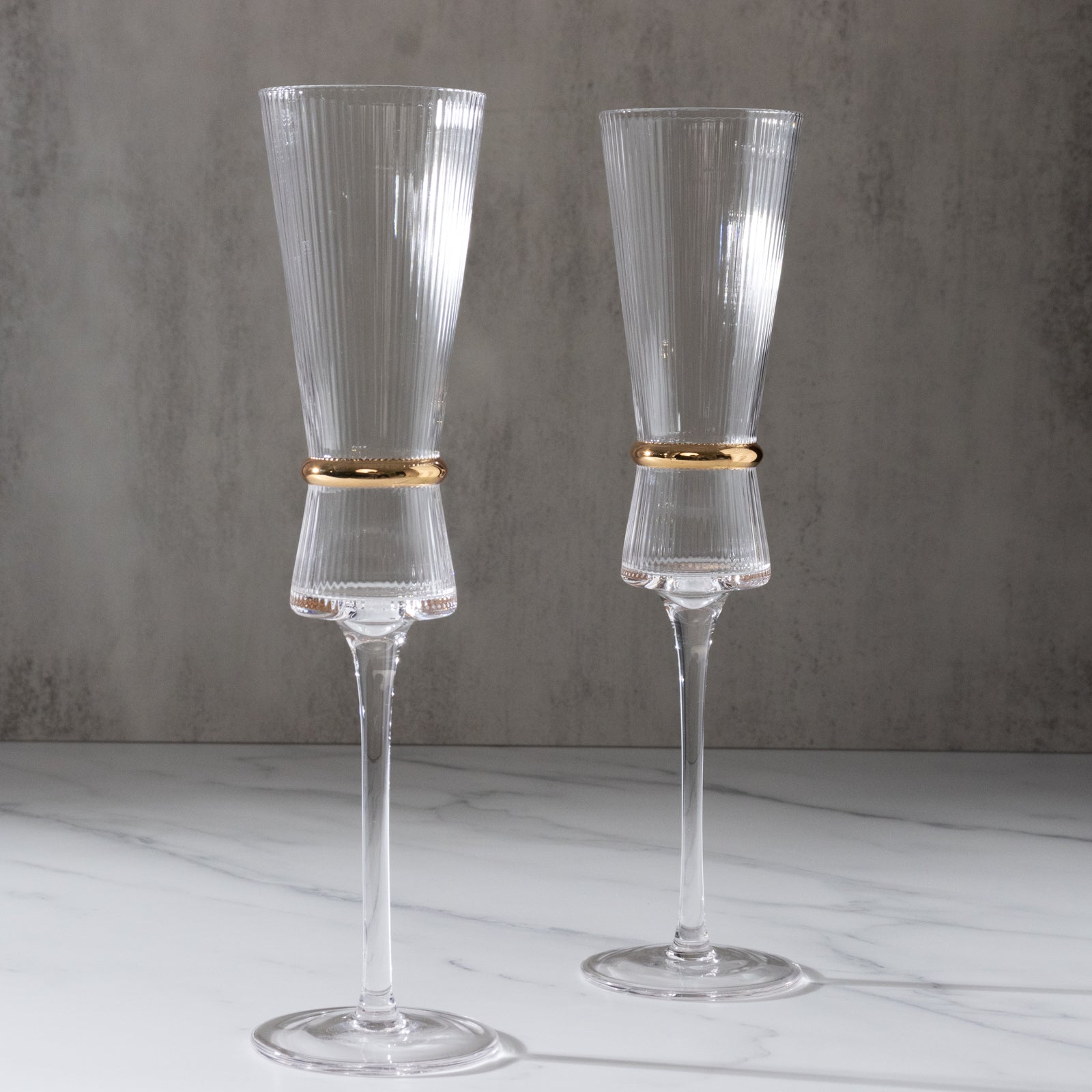 Clear champagne flutes with ribbed stem and gold ring accent. Elegant for celebrations.