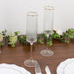 Clear modern champagne flutes with gold rim on a wooden table.
