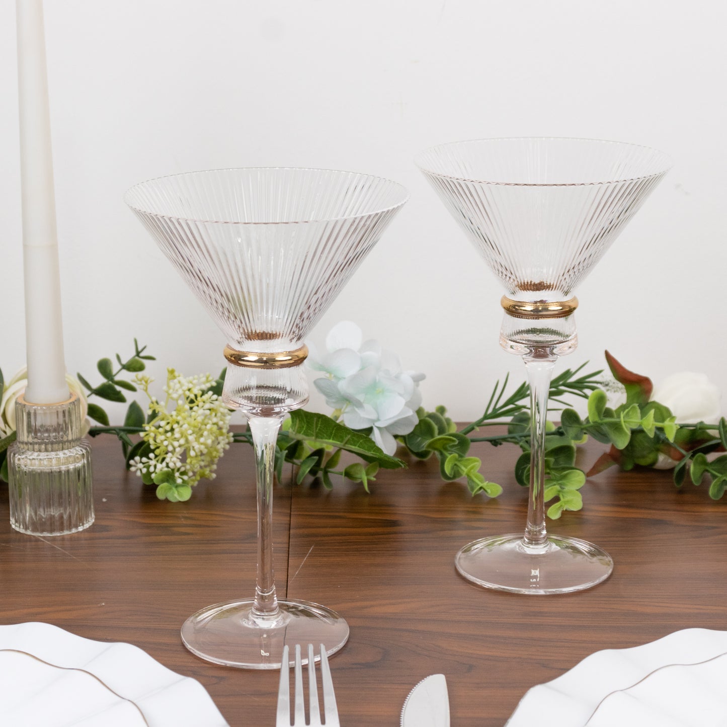Clear martini glasses with gold ring accents on a table setting.