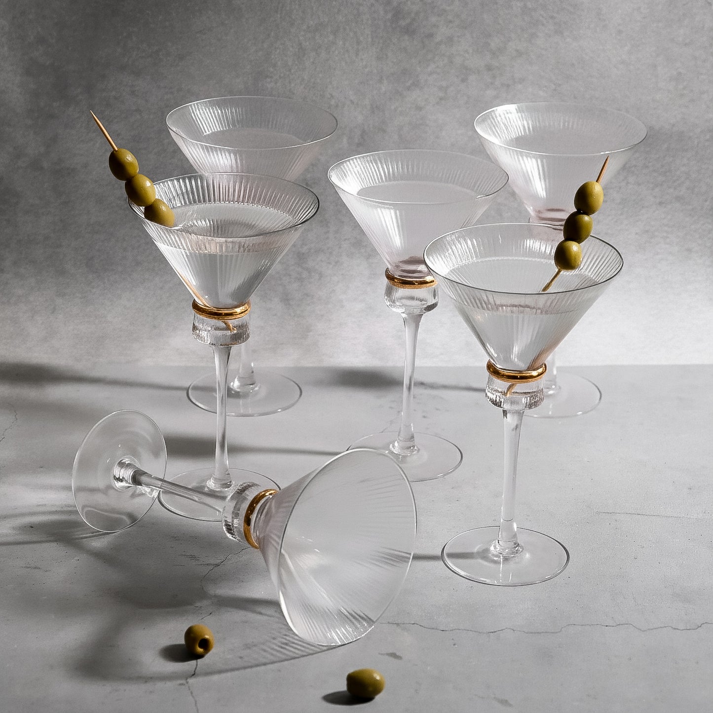 Clear martini glasses with gold ring accents and olives. Elegant ribbed design.