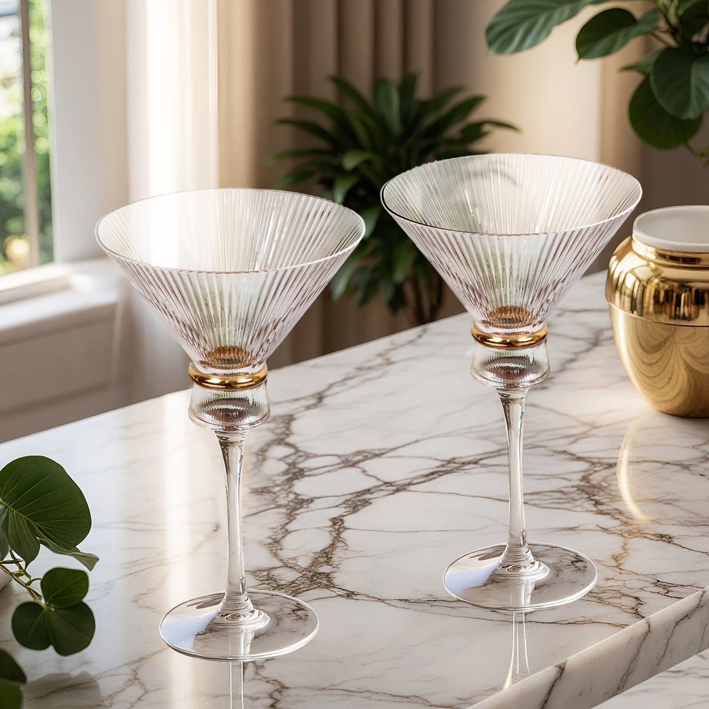 Clear martini glasses with ribbed design and gold ring accent on marble surface.
