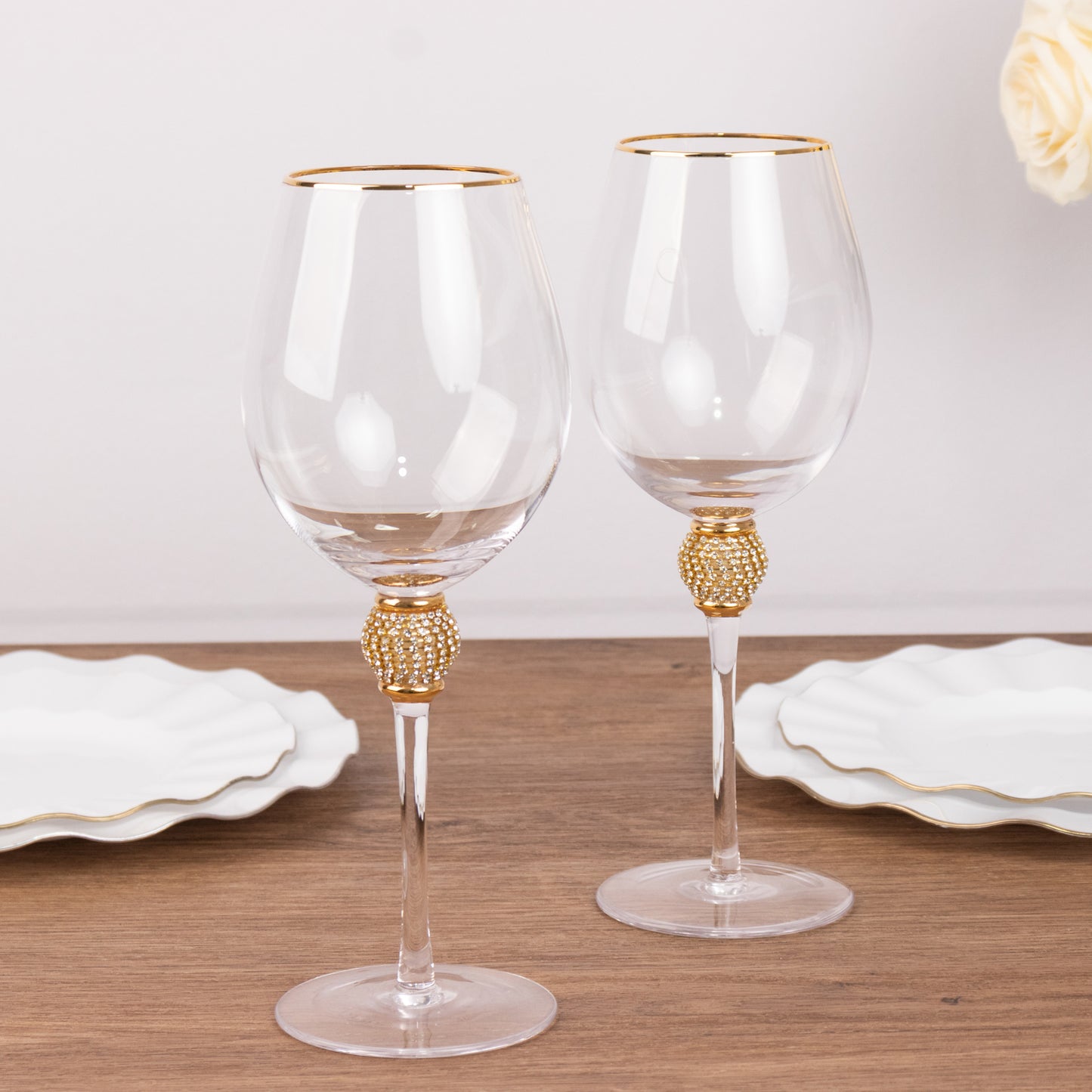 Gold rimmed crystal wine goblet glasses with rhinestone-studded stems.