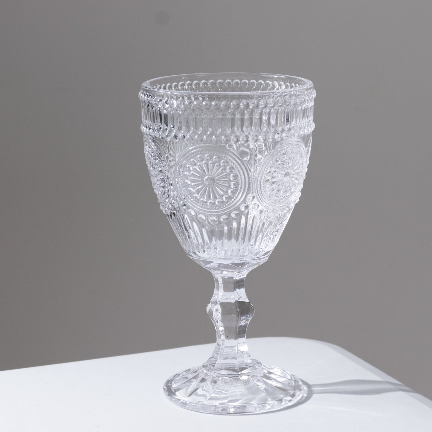 Clear vintage embossed glass goblet with floral design.