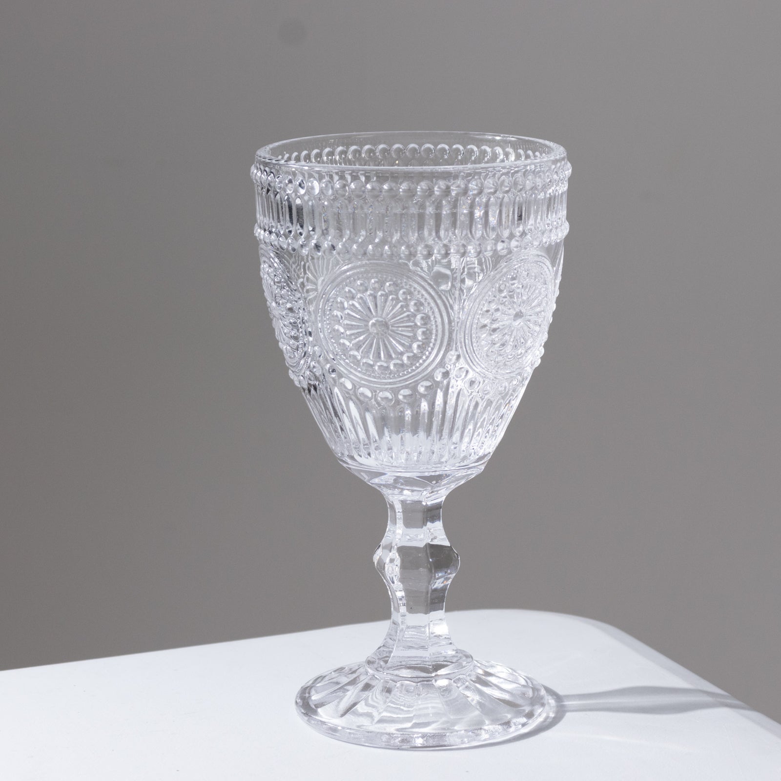 Clear vintage embossed glass goblet with floral design.