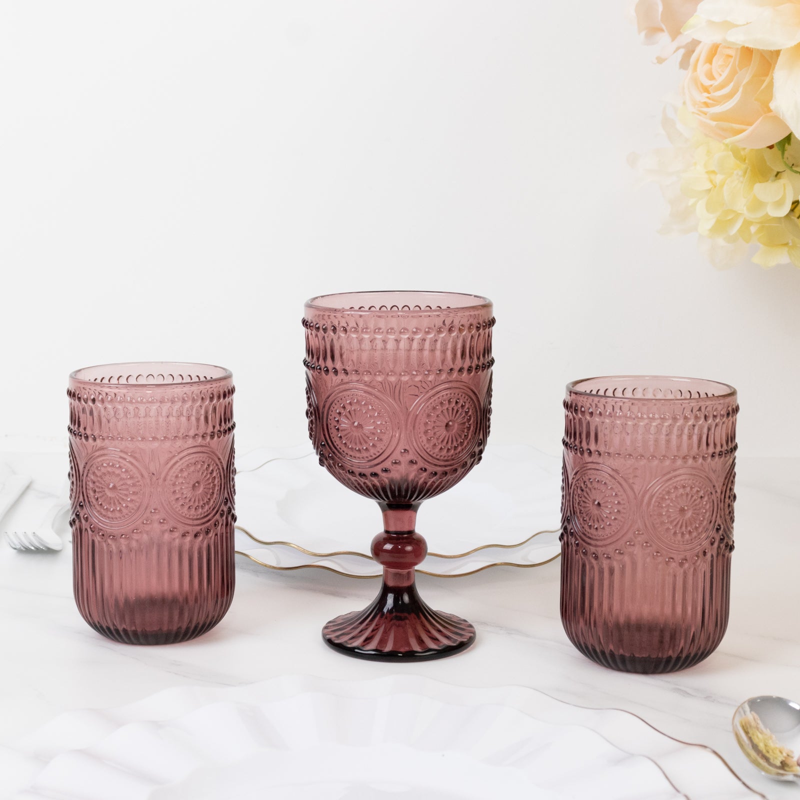 Dusty rose vintage embossed goblet wine glasses set on a table.