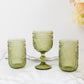 Dusty sage green vintage embossed goblet wine glasses on a marble surface.