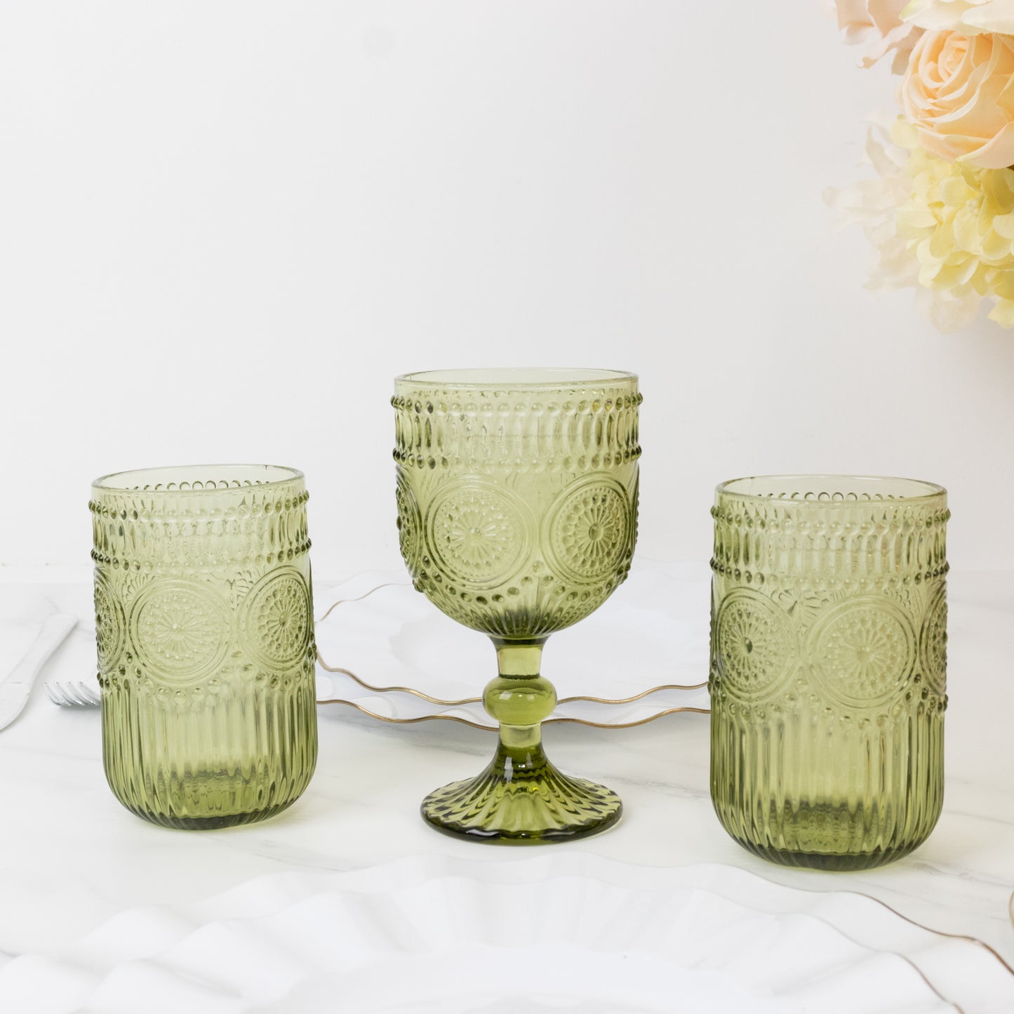 Dusty sage green vintage embossed goblet wine glasses on a marble surface.