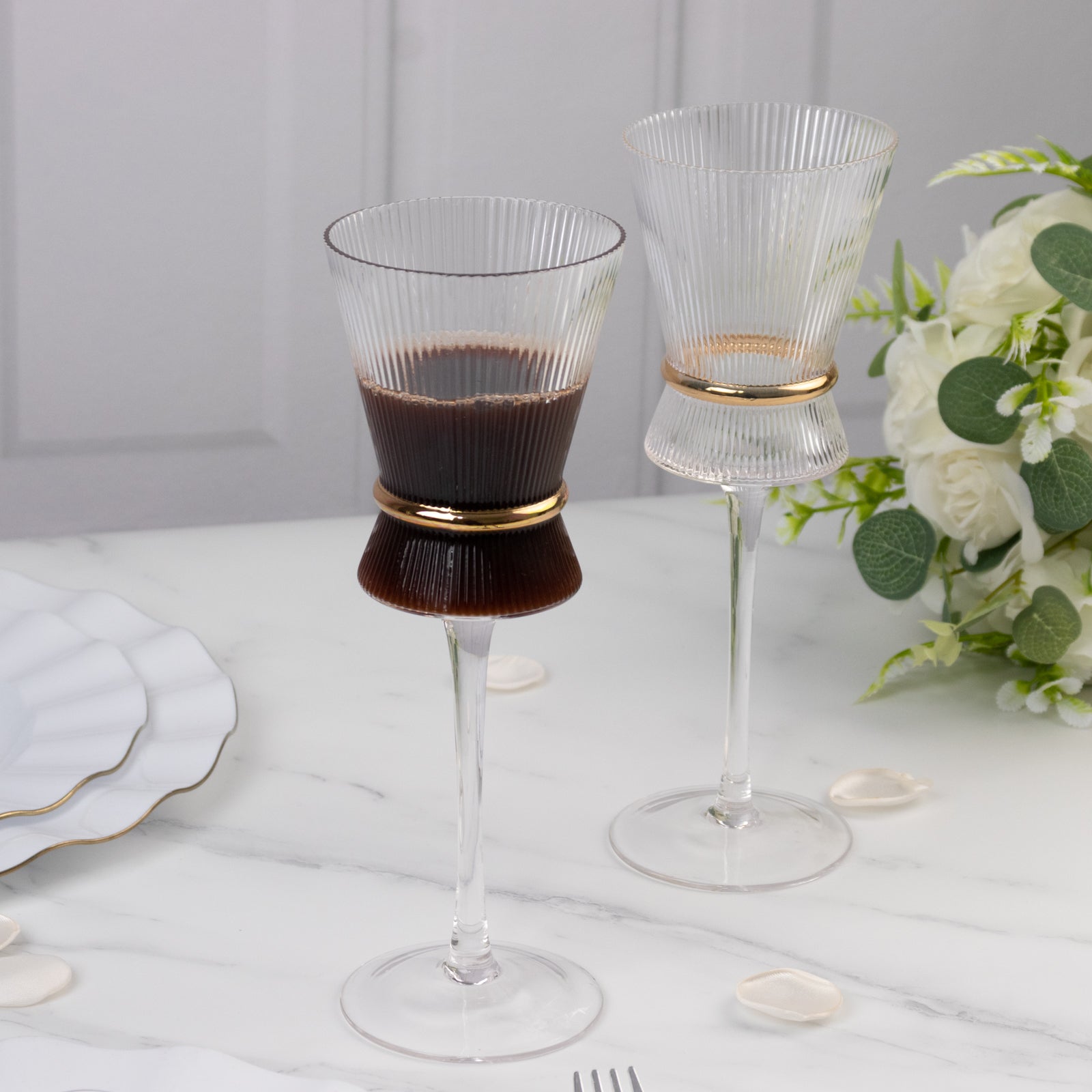 Clear wine glasses with ribbed design and gold ring accent. Elegant glassware for celebrations.