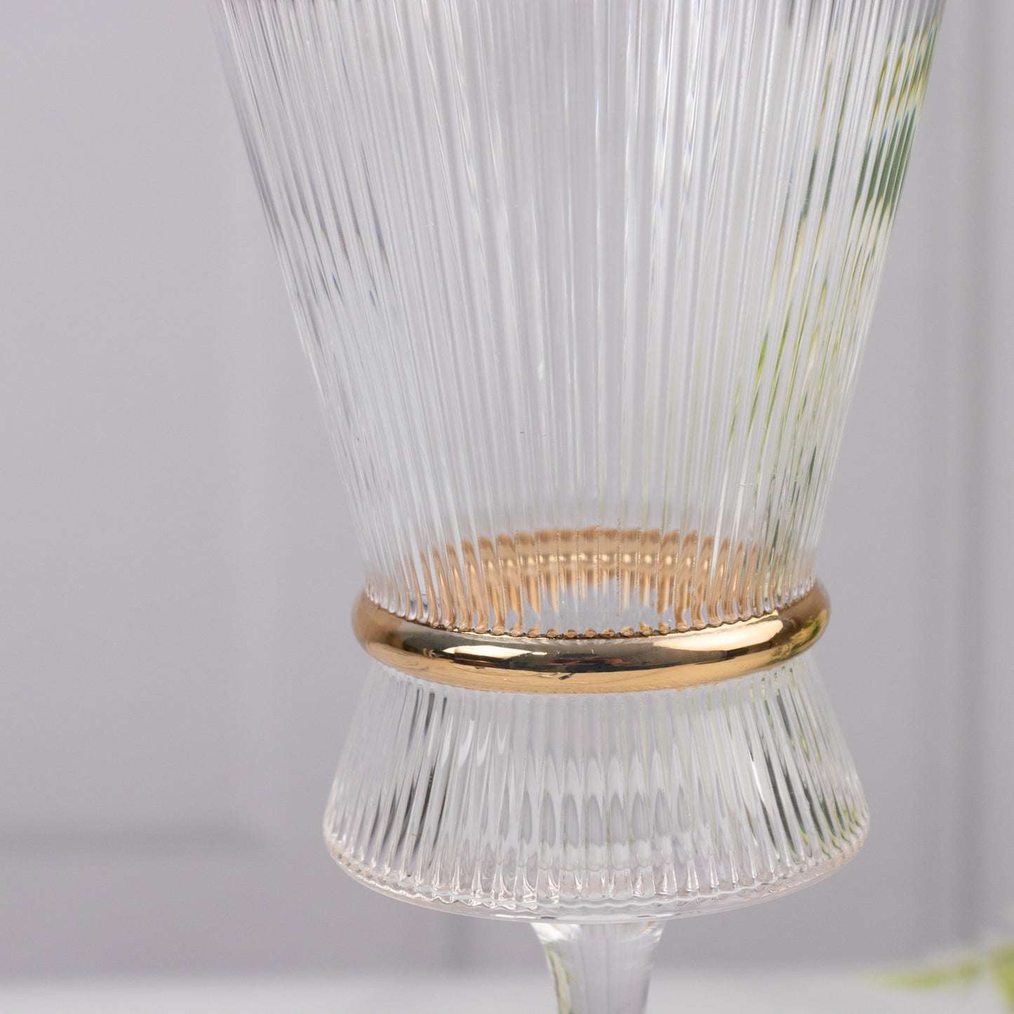 Clear wine glass with ribbed design and gold ring accent.