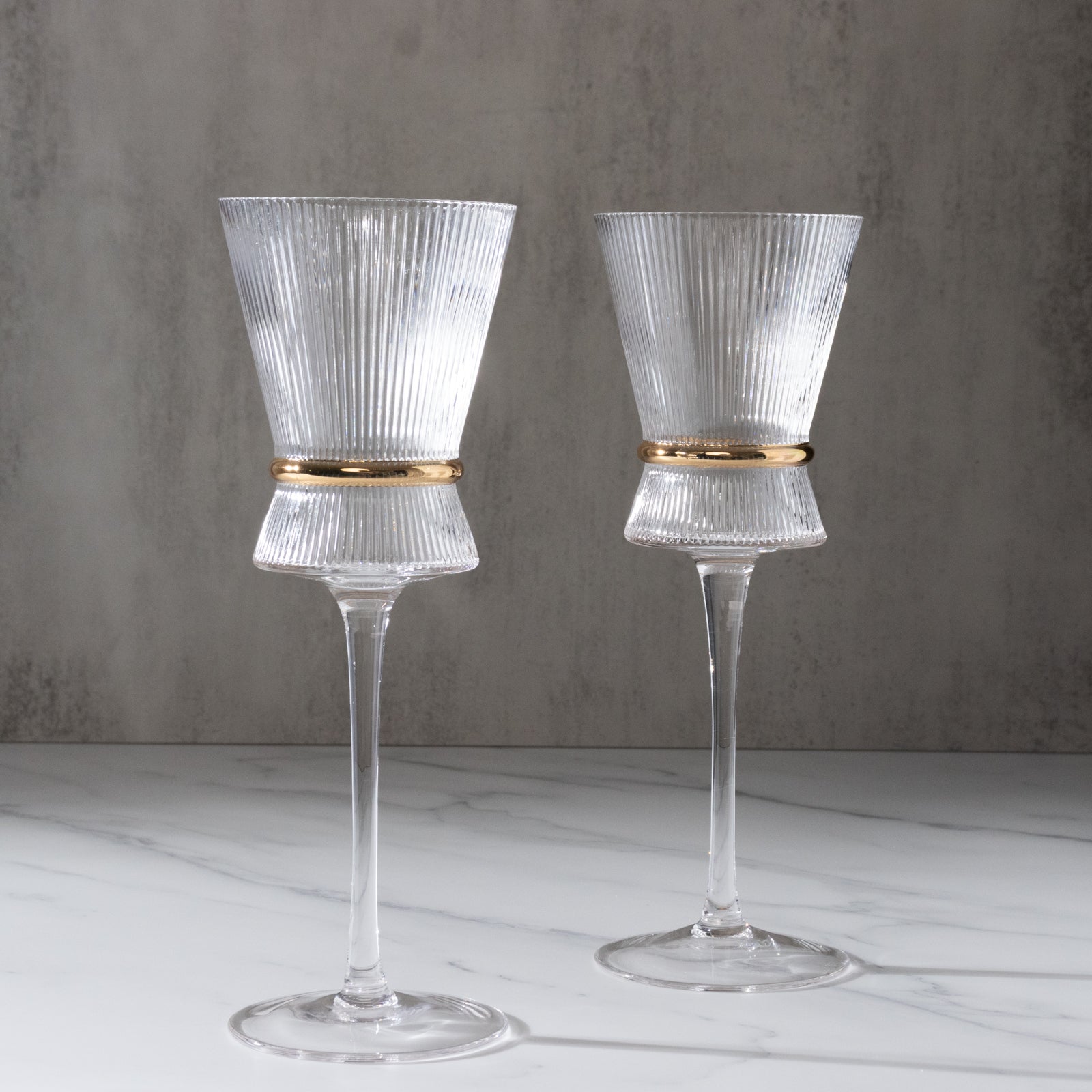 Clear wine glasses with ribbed design and gold ring accent, elegant glassware.